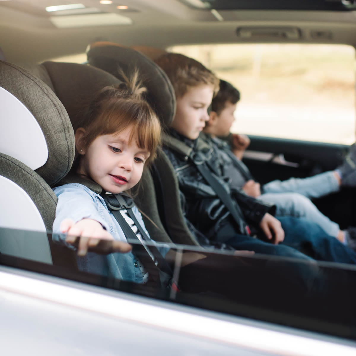 Three kids buckled safely in the back seat